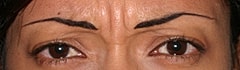 Close-up of a woman's face against blue backdrop.