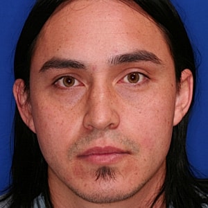 Portrait of a man with long black hair.