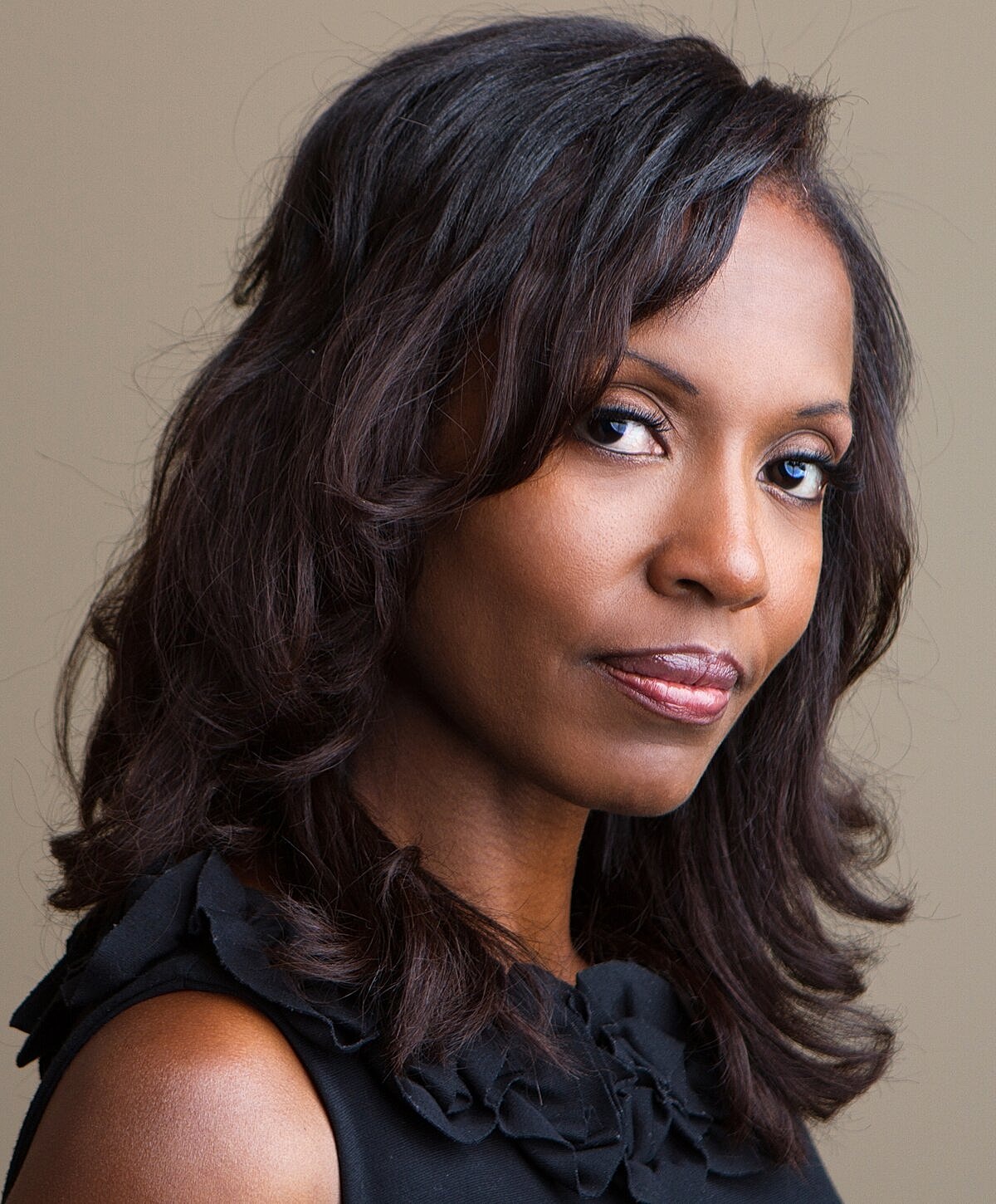 Orange County chin implant model with wavy hair in a black top.