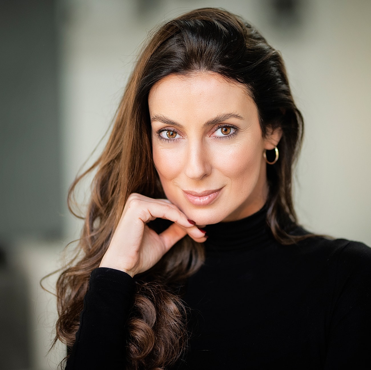 Smiling woman with long hair in black turtleneck.