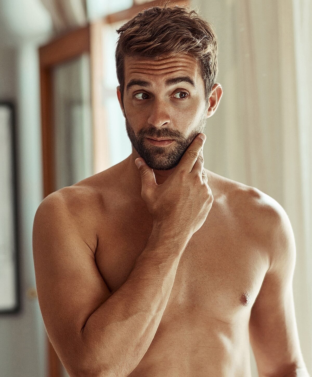 Orange County gynecomastia surgery model contemplating in front of a mirror.