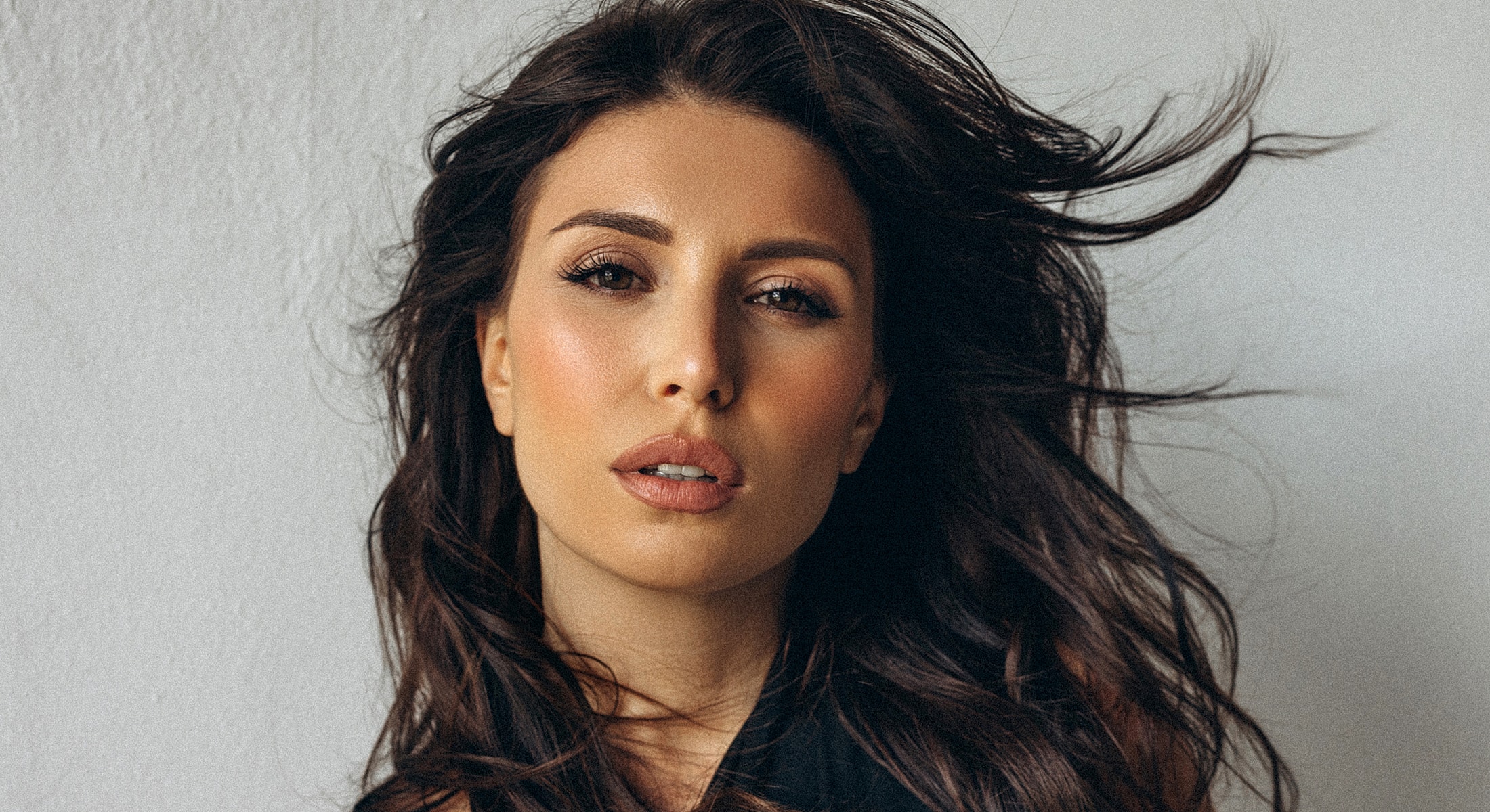 Orange County chin implant model with flowing hair, natural makeup, serious expression.